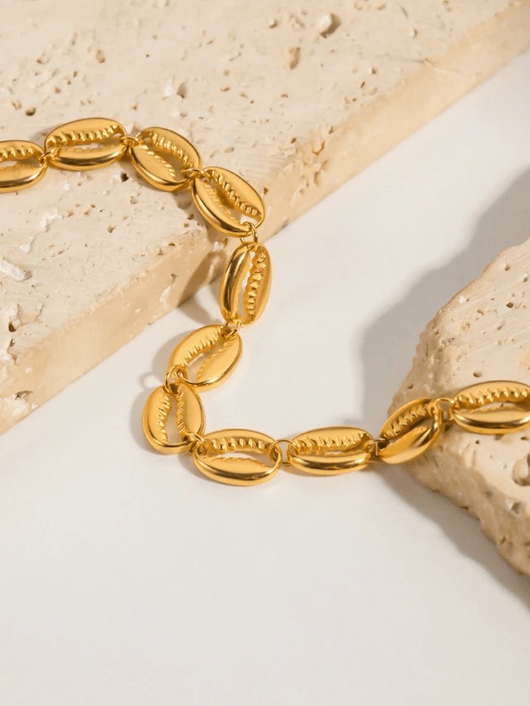 Bracelet cauris doré gros plan sable