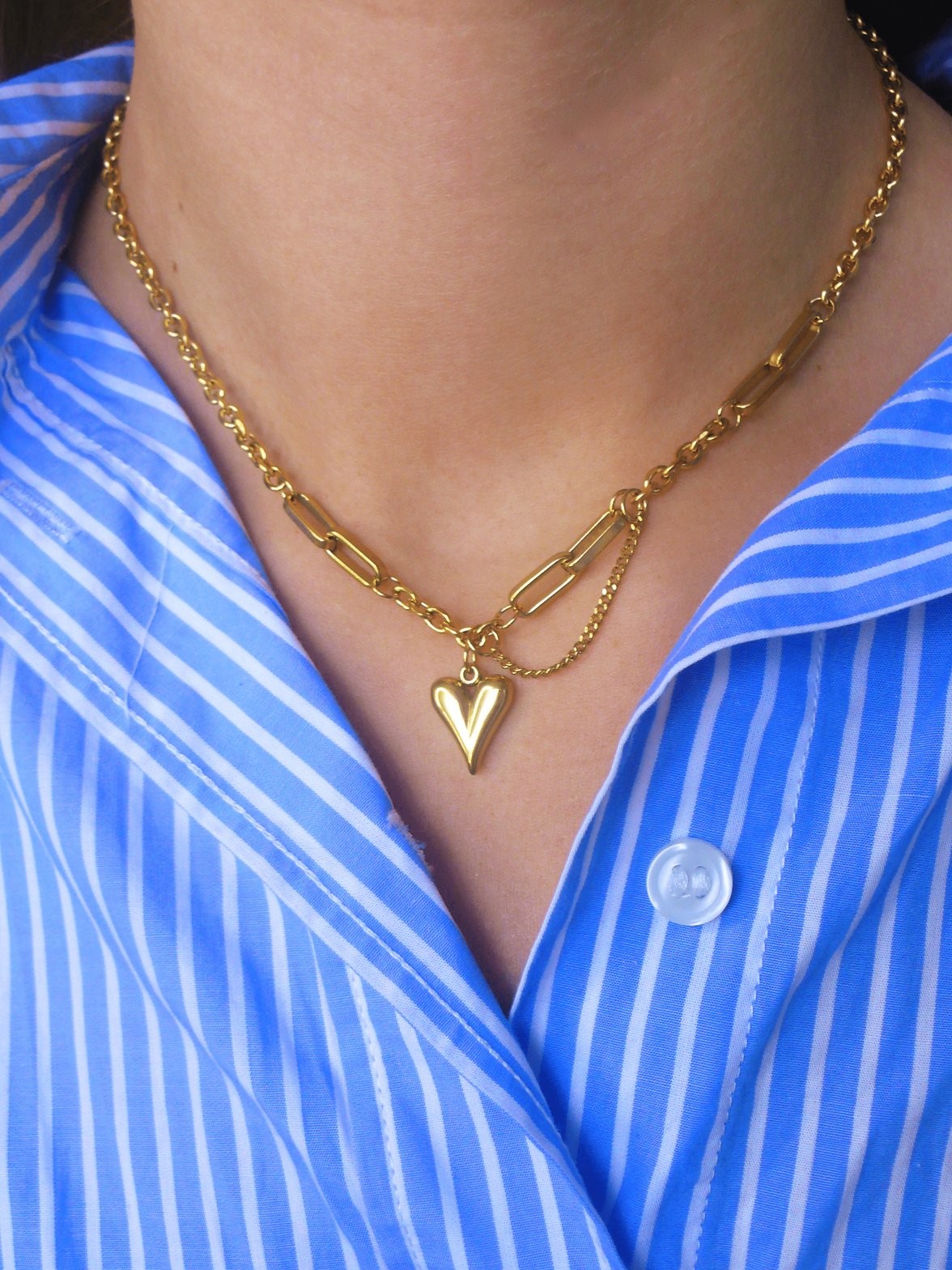 Collier doré avec pendentif cœur sur chemise rayée velours