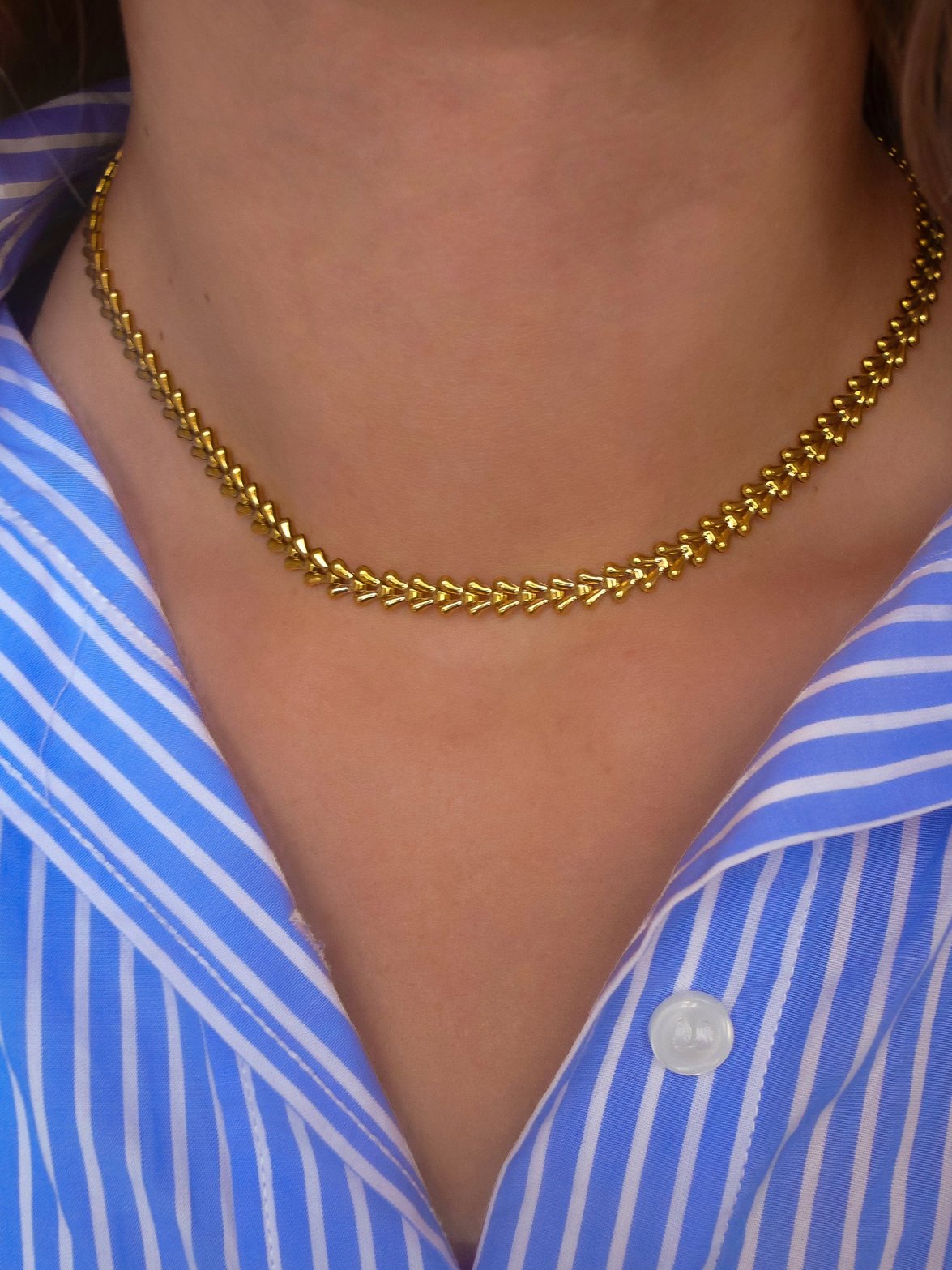 Collier chevron doré élégant porté soleil