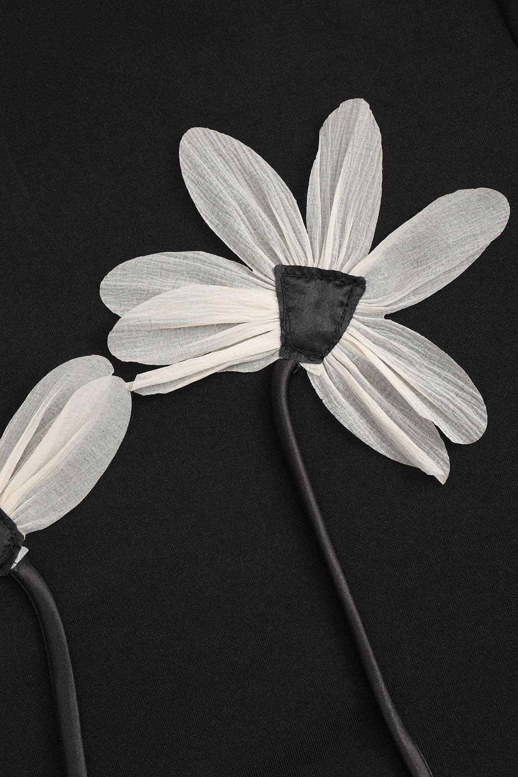 Détail des appliques florales sur pull noir élégance