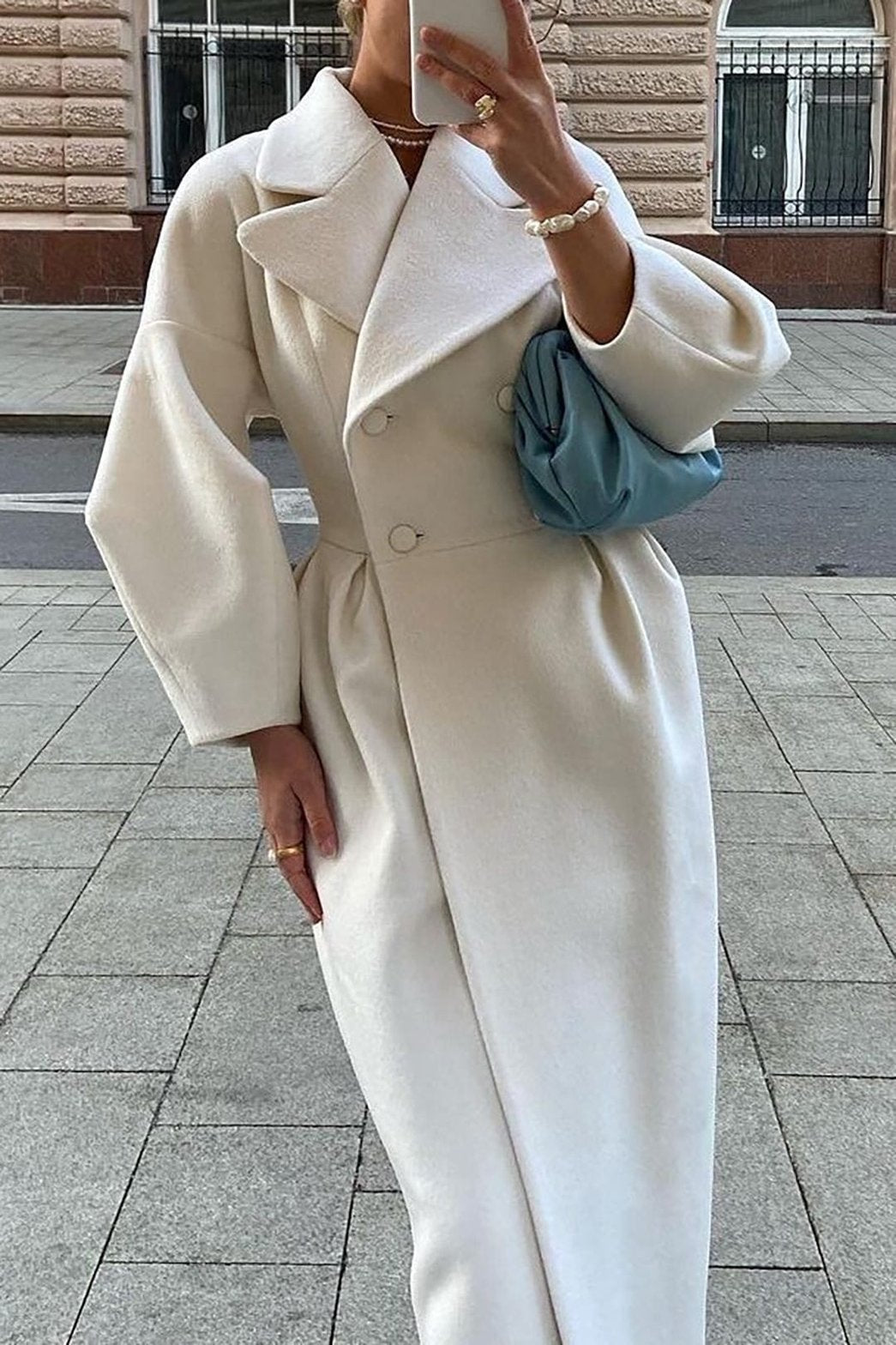 Trench-coat blanc crème élégant porté avec sac bleu doux