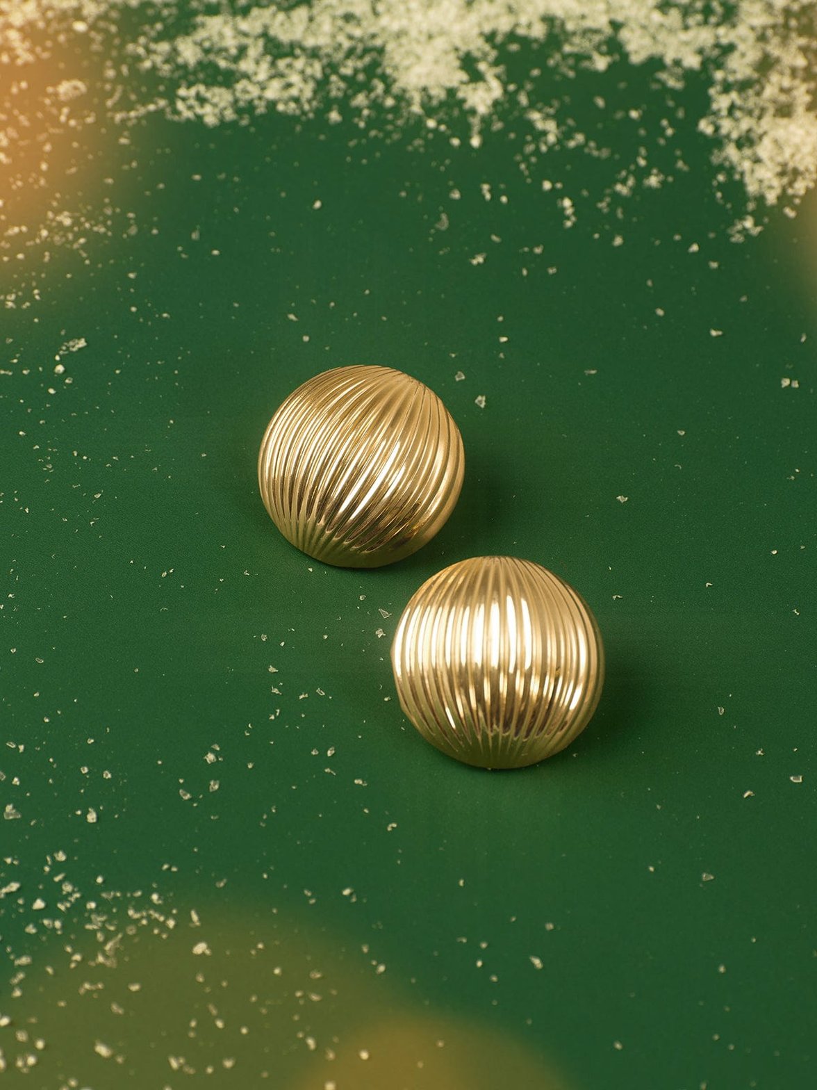 Boucles d'oreilles dorées cannelées sur fond vert émeraude