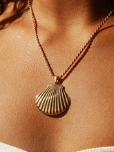 Collier coquillage doré porté sur peau bronzée soleil