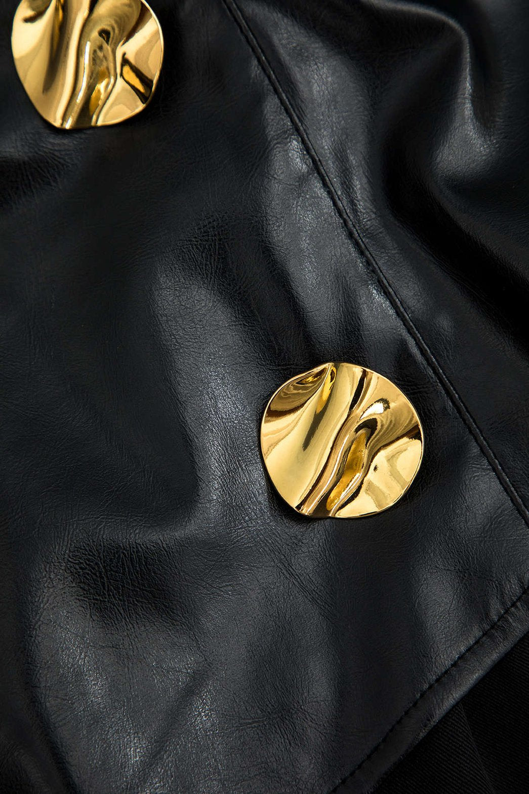 Détail des boutons dorés sur le pantalon noir brillant