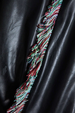 Détail des franges décoratives sur pantalon noir soleil