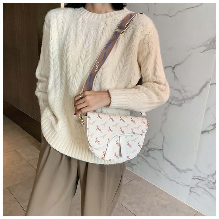 Sac bandoulière blanc jolieandjuliette motif logo porté avec pull crème et pantalon beige