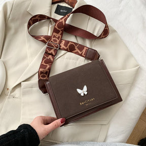 Sac bandoulière marron jolieandjuliette avec papillon blanc et sangle logotypée sur veste crème