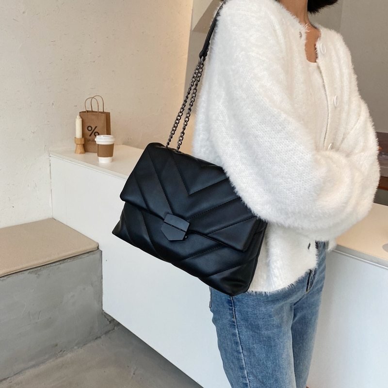 Sac bandoulière noir matelassé jolieandjuliette avec chaîne élégante porté par femme