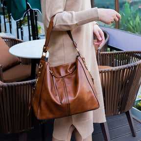 Sac hobo cuir cognac jolieandjuliette porté sur terrasse de café tenue beige élégante