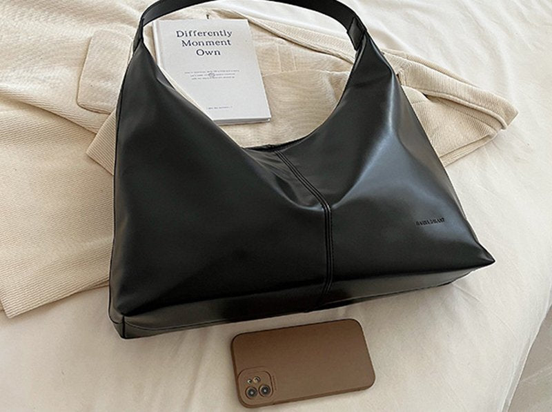 Sac hobo noir jolieandjuliette en cuir minimaliste élégant avec livre et smartphone