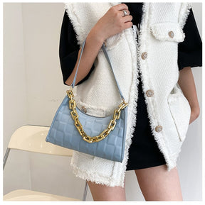 Sac à main bleu ciel jolieandjuliette avec chaîne dorée, porté avec tenue élégante blanche et noire