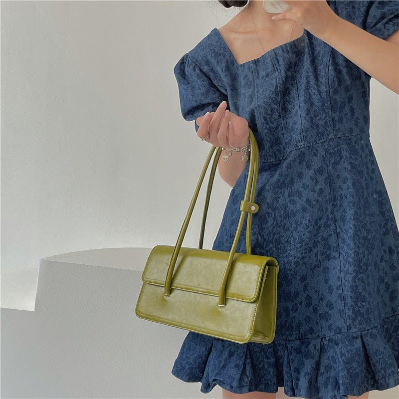 Sac à main vert olive jolieandjuliette rectangulaire élégant style rétro tenu par femme en robe bleue